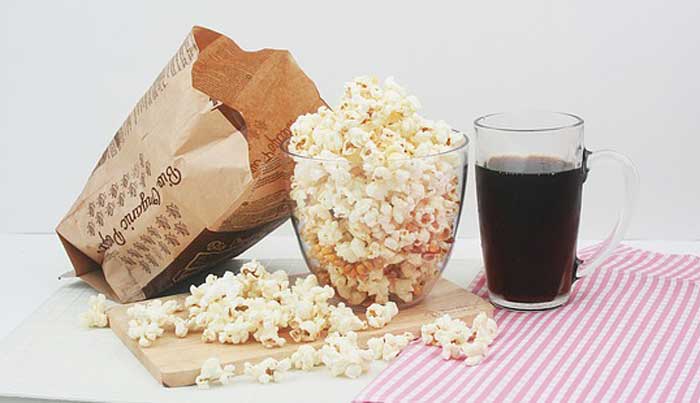 microwave popcorn in a glass container along with a refreshing drink