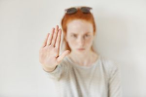 fluoroquinolone-a young redheaded lady-holding up her hand-making a stop motion