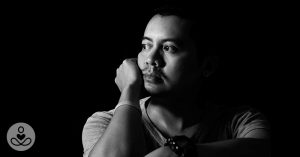 man staring away with hand on his cheek
