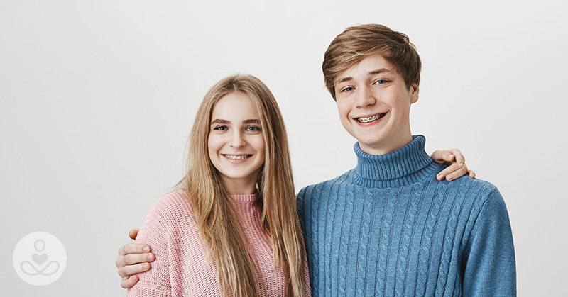 girl in pink sweater hugging her brother in a blue ribbed turtleneck