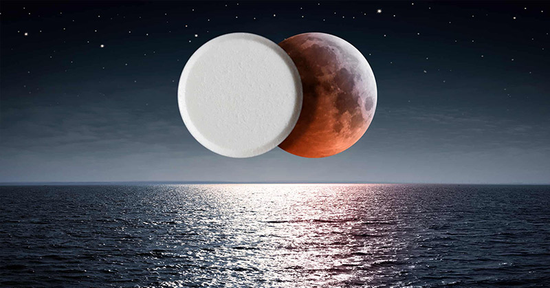 pill on top of a blood moon reflected over calm waters