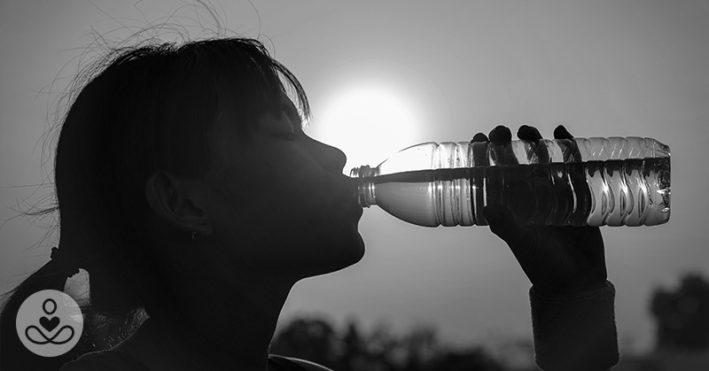 black and white image of woman drinking from a bottle of water