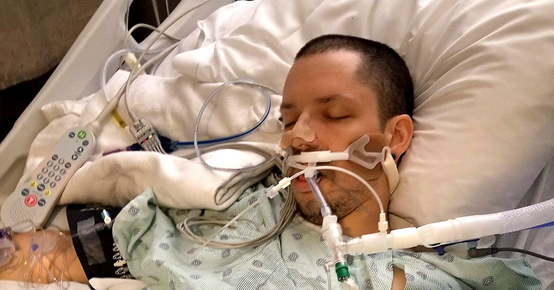 man with breathing tubes in a hospital bed