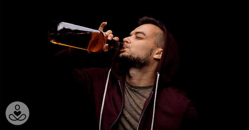 man in a hoodie drinking alcohol from the bottle