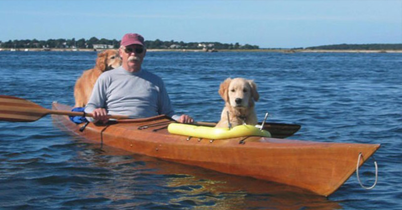 man with dogs in kayak
