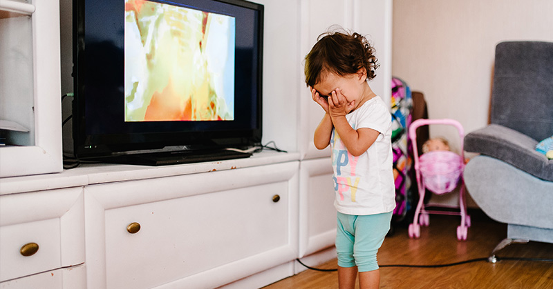 crying toddler in front of television