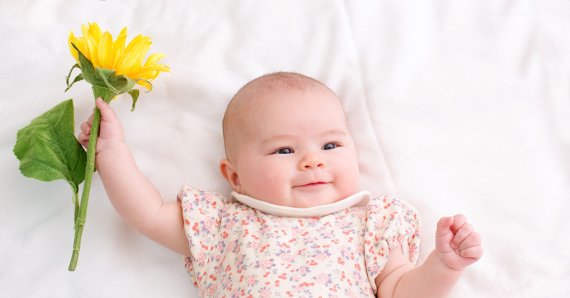 baby holding yellow flower