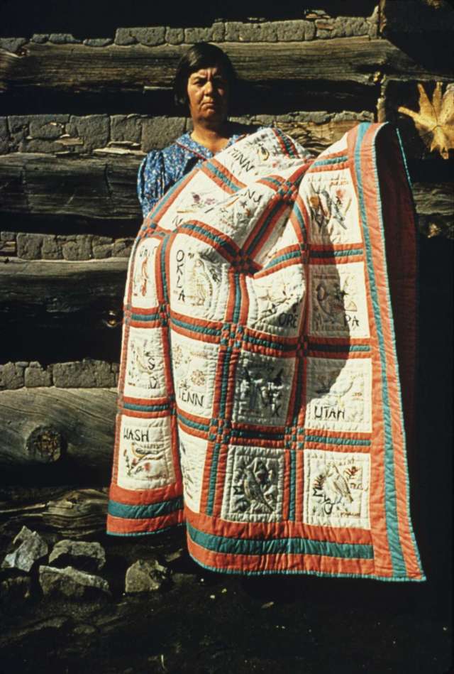 A woman holding a homemade quilt