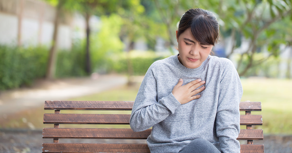 woman on park bench suffering from acid reflux symptoms