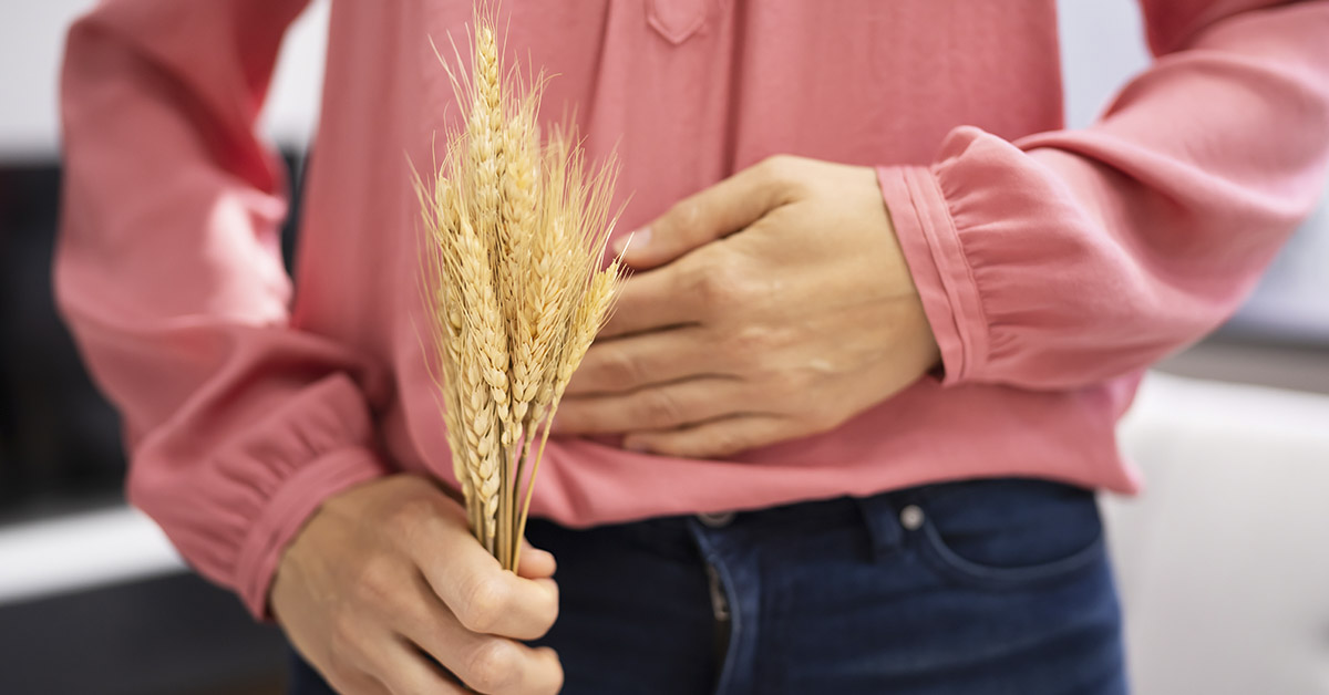 Person holding wheat with hand placed over stomach