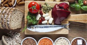 various foods such as liver, fish, legumes, vegetables on a cutting board.