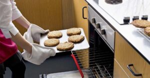 High School Introduces Classes That Teach Students How To Adult Including Cooking, Money Management, And Home Skills putting cookies in the oven