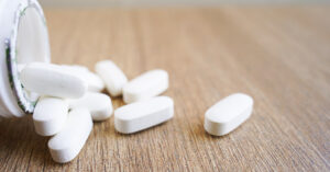 Calcium Supplements: Should You Take Them? white tablets spilled onto a table from bottle