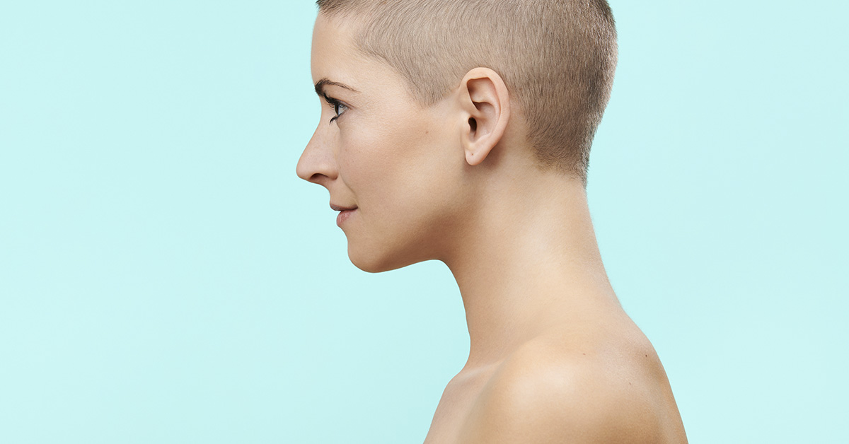 profile of woman with shaved head, light blue background