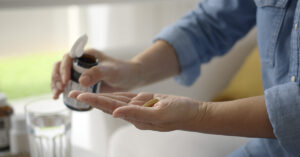 person dispensing pills into palm of hand
