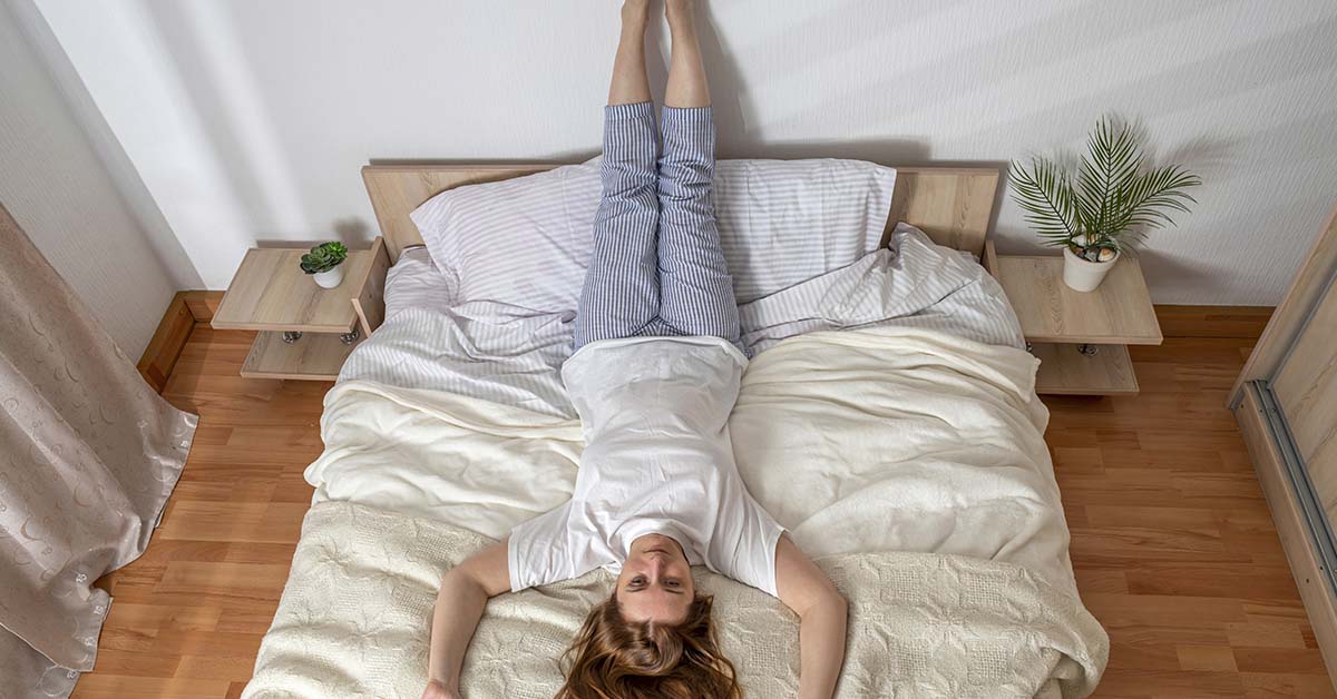woman laying on bed with feet up on the wall