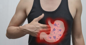 illustration of stomach overlaying man in black tank top touching abdomen