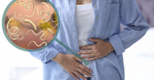 7 Signs Of Intestinal Parasites Living Inside Your Body person holding abdomen depiction of someone with intestinal parasites