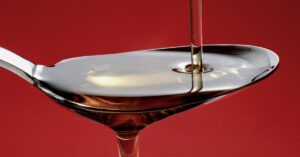 Healthy or Horrible? 5 Benefits of Palm Fruit Oil teaspoon with palm fruit oil being poured onto it