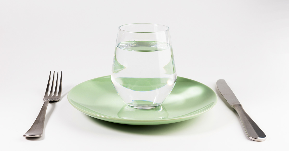 water fasting concept. A glass over water placed on a plate with a knife and for placed bside