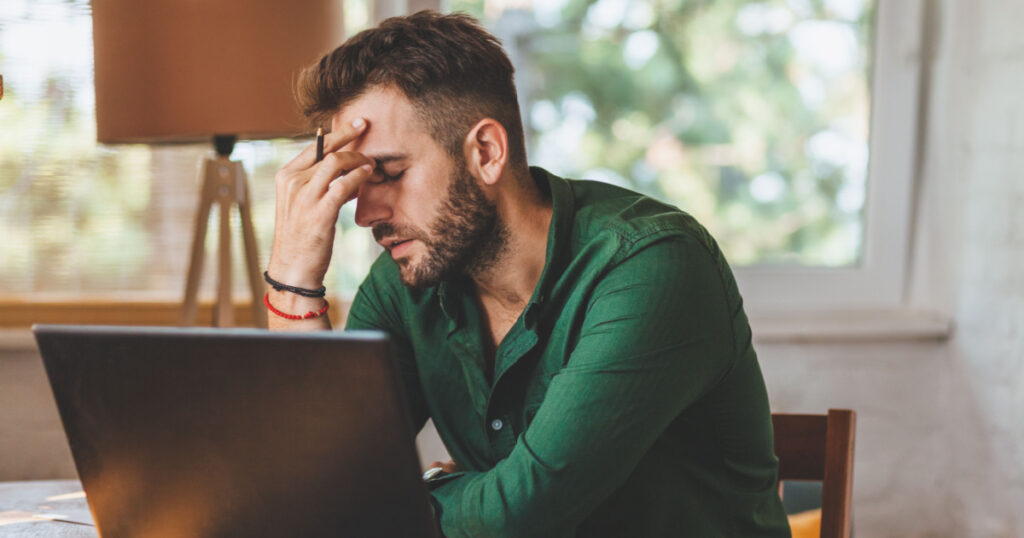 Young man having stressful time working on laptop