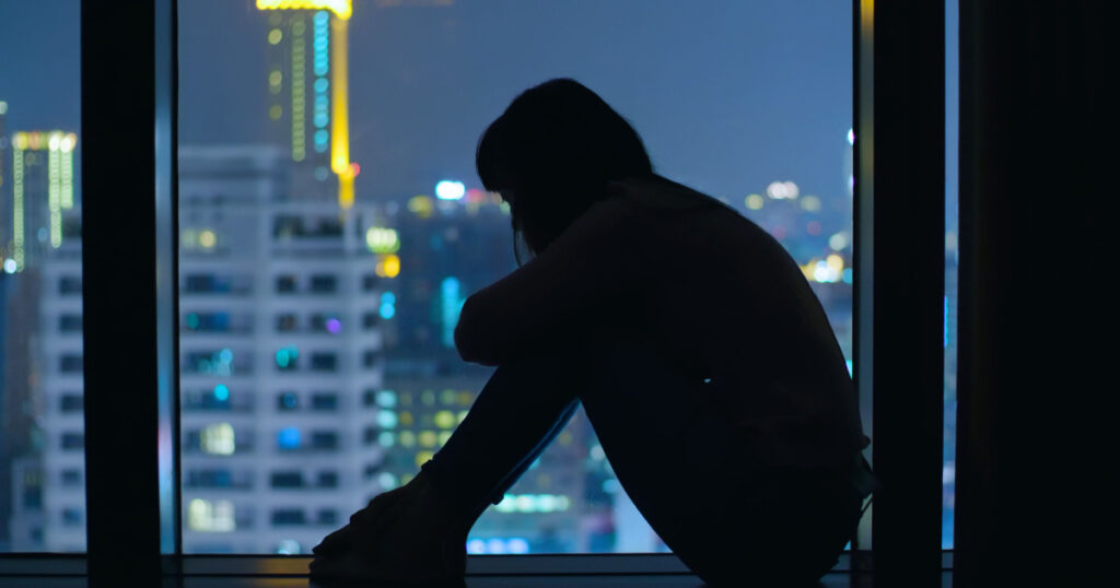 woman sit in window feeling depression at night