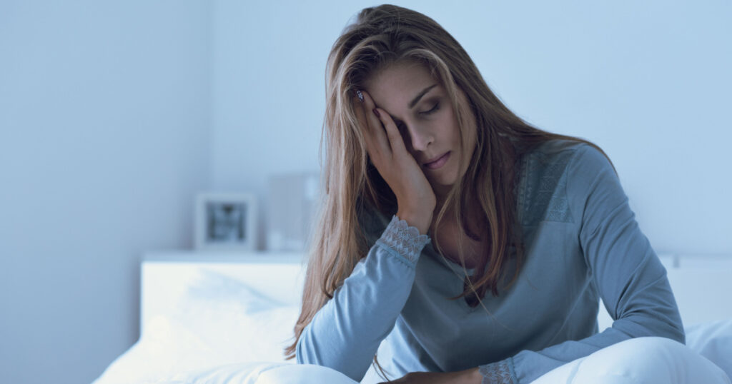 Depressed woman awake in the night, she is touching her forehead and suffering from insomnia