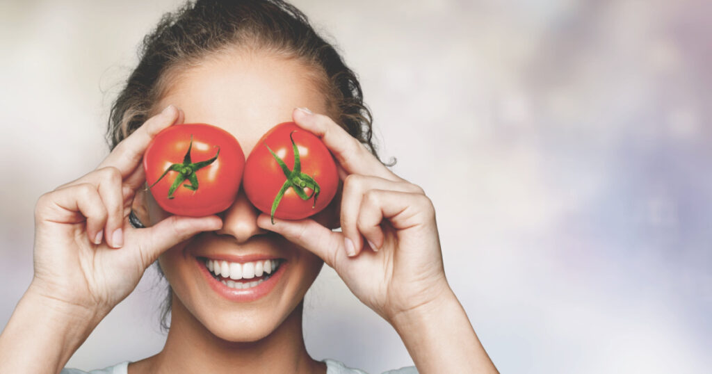 laughing woman holding two ripe tomatoes