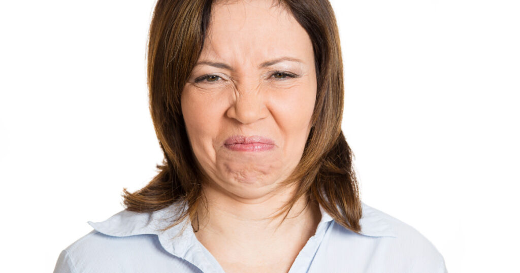Closeup, headshot unhappy woman wrinkling nose and face, looks displeased
