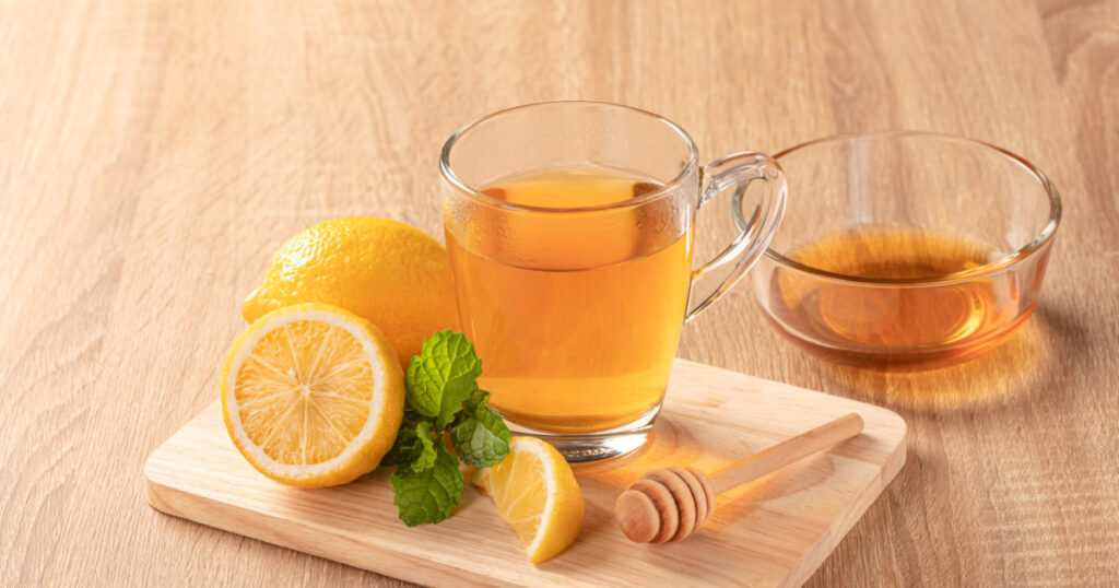 Glass cup of tea with lemon , honey and mint on wooden table to get rid of phlegm and mucus