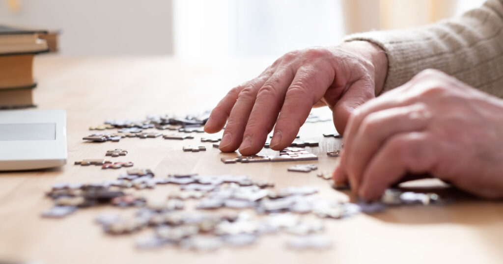 Senior male hands working on a puzzle at home