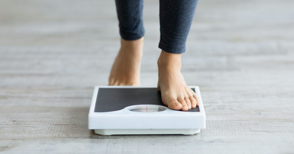 woman stepping on scales to measure her weight 
