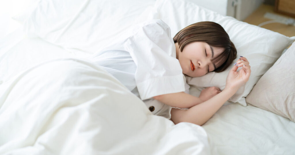 Female sleeping on a bed in a bright room
