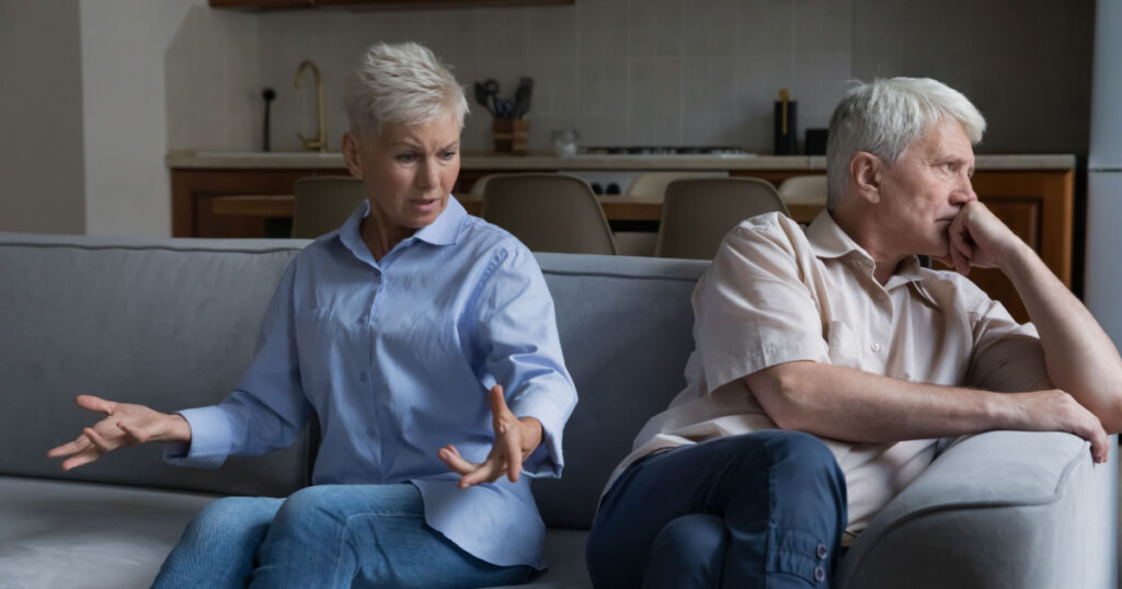 Wound up older wife expresses her displeasure to annoyed husband sit together on sofa at home