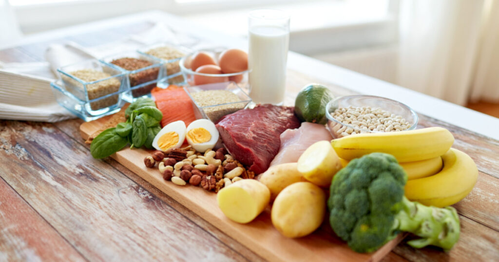 balanced diet, cooking, culinary and food concept - close up of vegetables, fruit and meat on wooden table