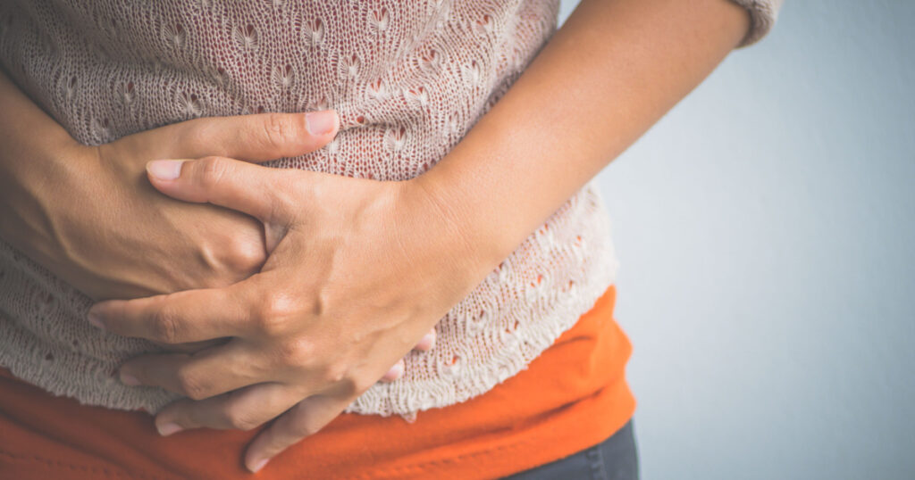 woman clasping stomach due to pain from acid reflux
