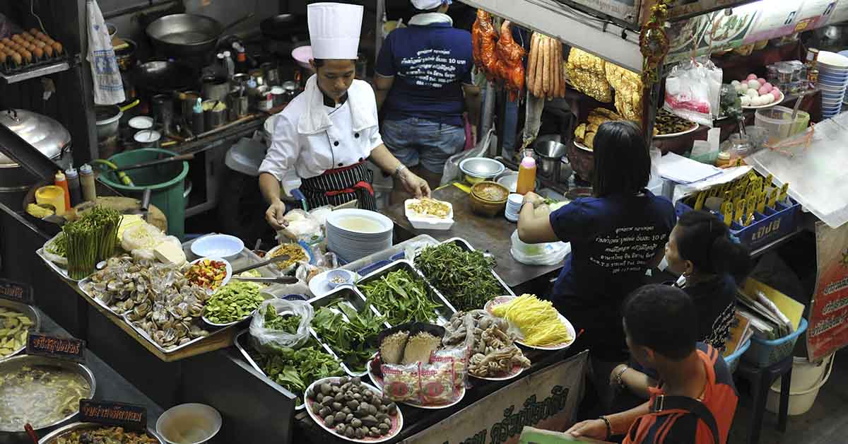 Unidentified vendors serve food to customers at a streetside restaurant on Dec 13, 2012 in Bangkok, Thailand
