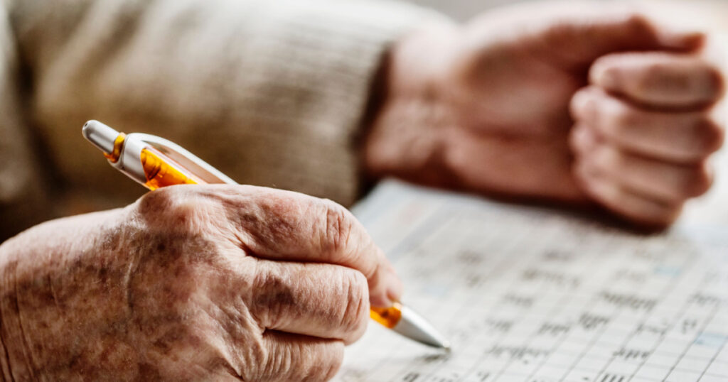 hand of a senior woman , sudoku, crossword
