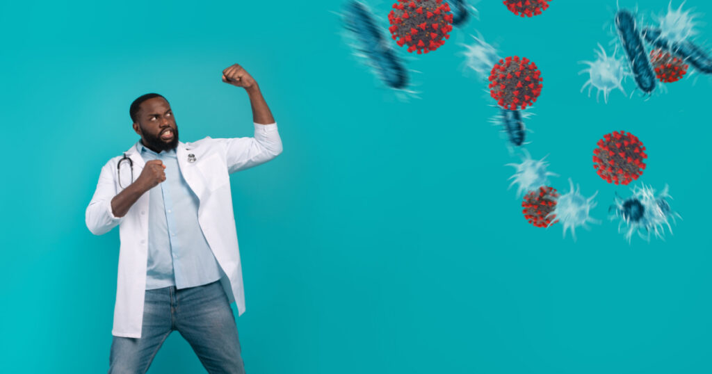 Doctor fighting with bare hands against bacteria and viruses on cyan background
