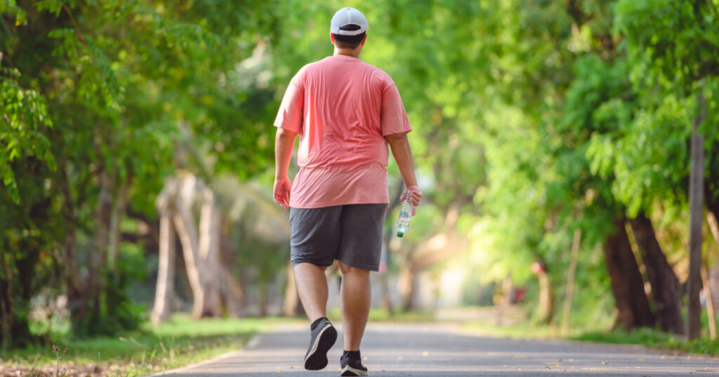 Fat man exercising By walking to burn fat And run slowly to exercise in the park
