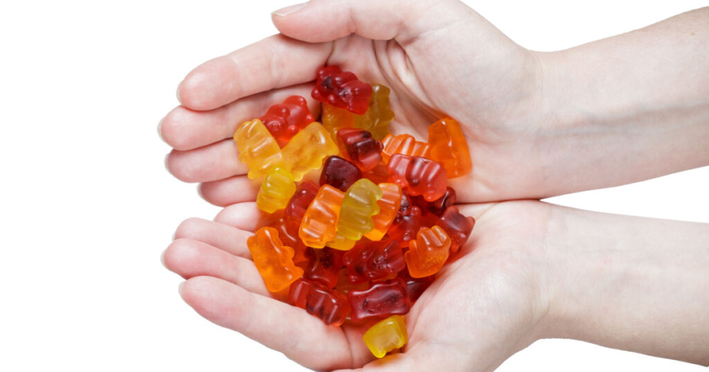 sweets in the hands of a girl isolated on white. jelly candy. Fruit jelly bears in different flavors and colors. top view. copy space
