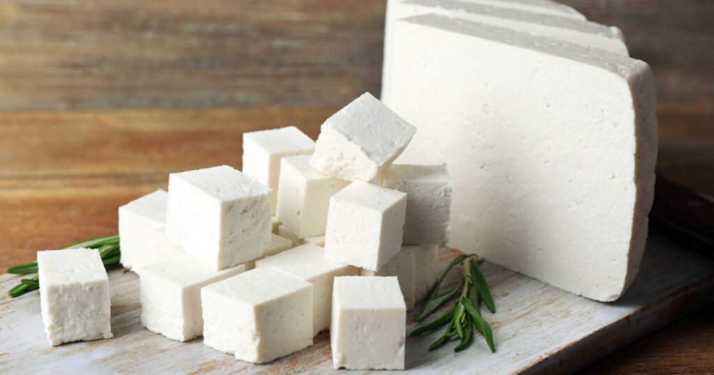 Sliced feta cheese with rosemary on table on wooden background
