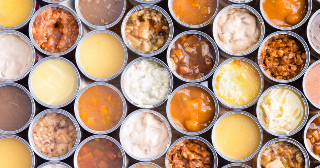 Colorful background of neatly arranged rows of opened cans of assorted soup viewed full frame from above in a food abstract still life
