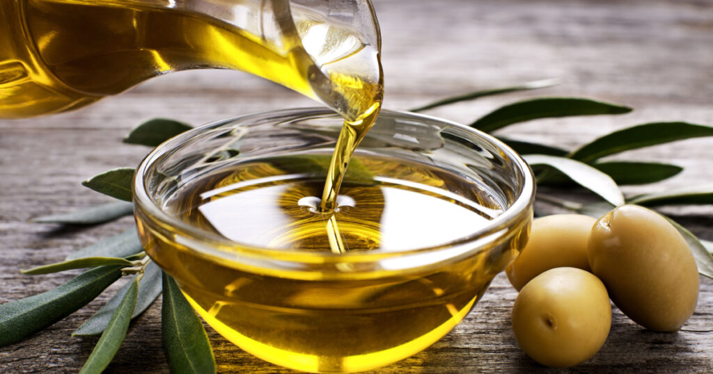 Bottle pouring virgin olive oil in a bowl close up
