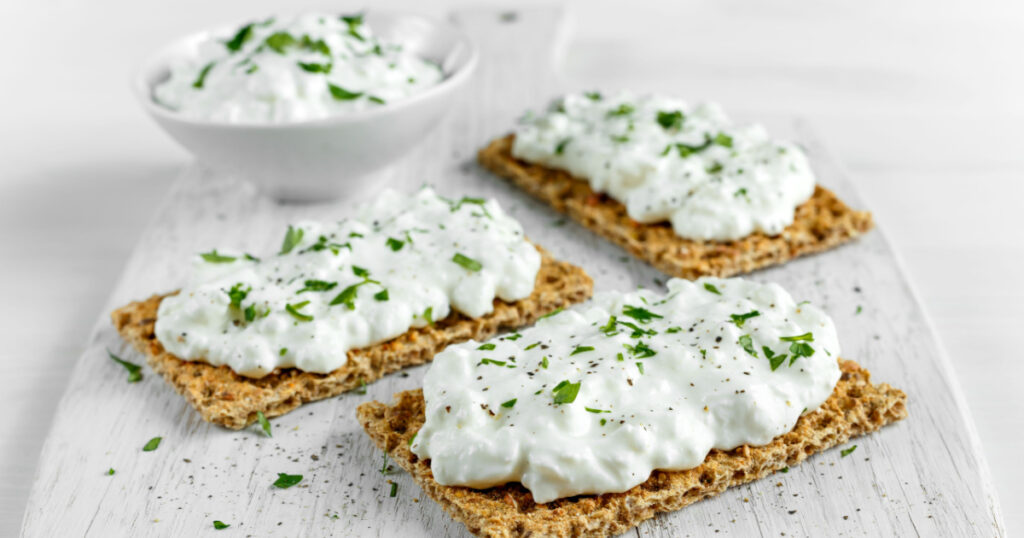 Homemade Crispbread toast weight loss foods with Cottage Cheese and parsley on white wooden board.
