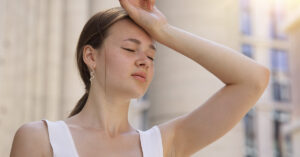 woman placing back of hand on head in discomfort