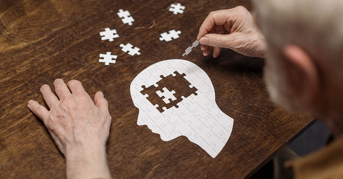 dementia concept, a person putting together puzzle, which is a white silhouette profile view of a head