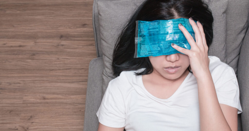 Top view of Asian woman with cold pack on her forehead for relief fever headaches and migraines
