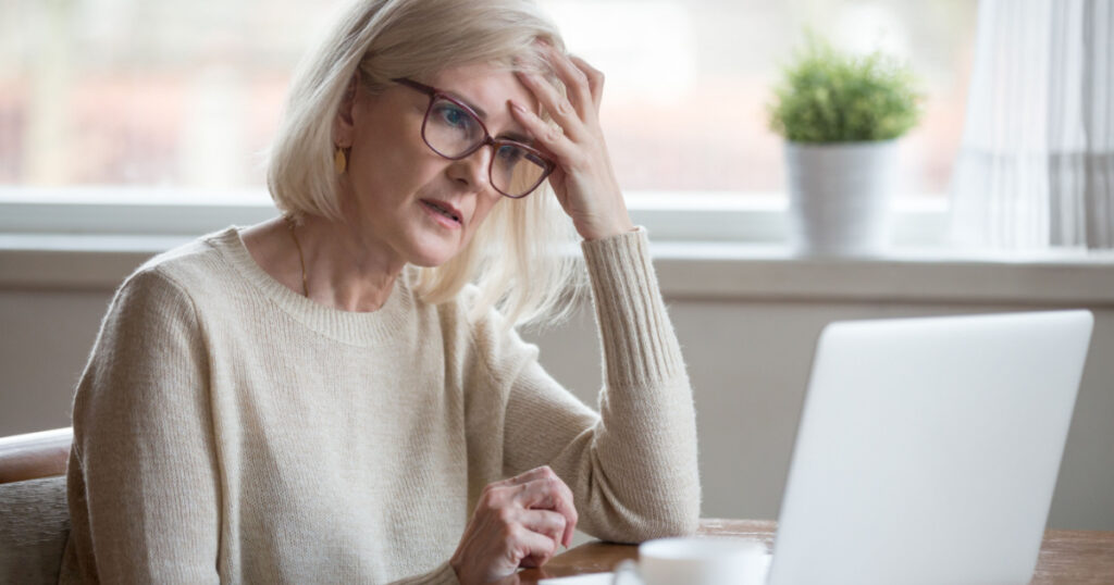 Thoughtful confused mature business woman concerned thinking about online problem looking at laptop, frustrated worried senior middle aged female reading bad email news, suffering from memory loss
