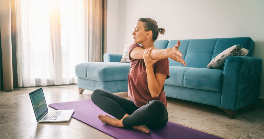 Attractive young woman doing yoga stretching yoga online at home. Self-isolation is beneficial, entertainment and education on the Internet. Healthy lifestyle concept.
